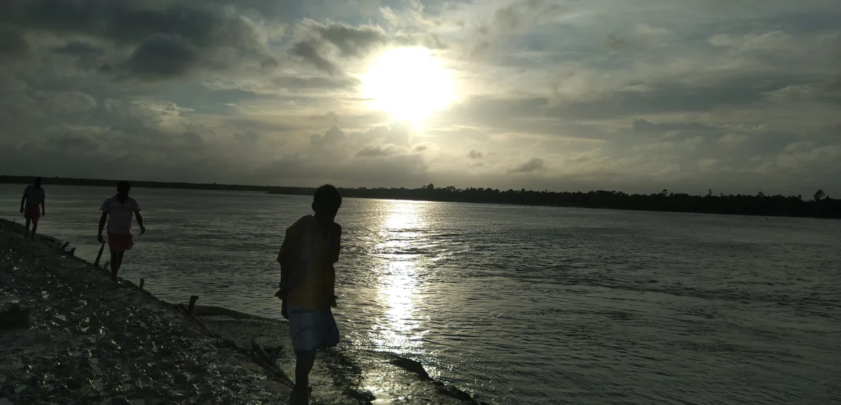 People walking beside a river at dawn