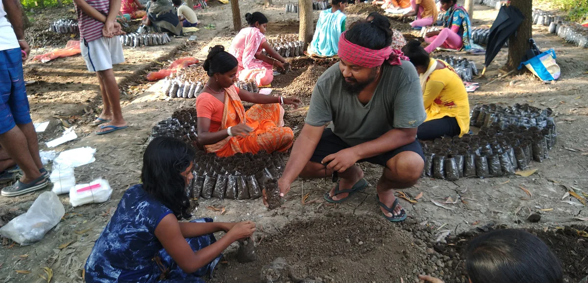 Saurav Moni preparing soil and saplings with villagers